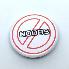 a button with the word noobs written in black and red on it, against a white background