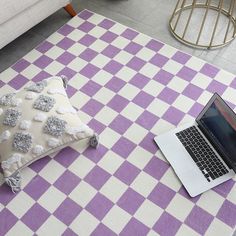 a laptop computer sitting on top of a purple and white checkered rug