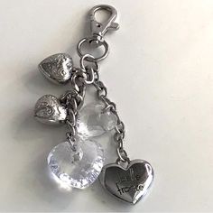 a heart shaped keychain with charms attached to it's sides on a white surface