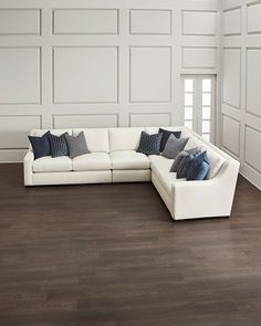 a large white sectional couch sitting on top of a hard wood floor