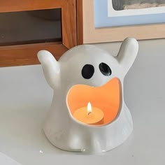 a white elephant shaped candle holder with a lit candle in it's mouth and eyes