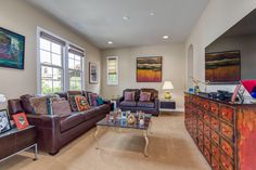 a living room filled with furniture and paintings on the wall above it's windows