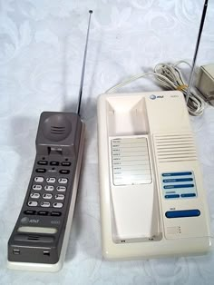 two old cell phones sitting next to each other on a white sheet with blue accents