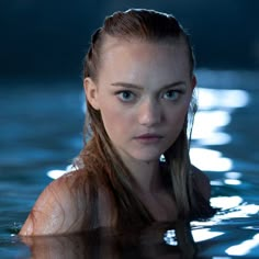 a woman in the water with long hair and piercings on her head is looking at the camera