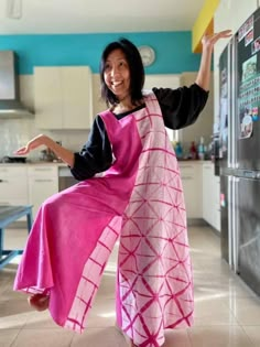 a woman standing in front of a refrigerator wearing a pink and black dress with geometric designs on it