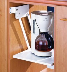 a white coffee maker sitting on top of a wooden cabinet