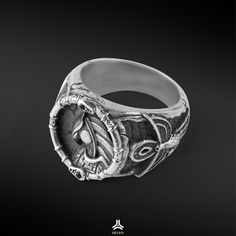 a silver ring with an image of a bird in the center on a black background