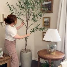 a woman standing next to a tree in a living room