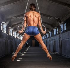 a shirtless man is swinging on a rope in an abandoned building - stock photo - images