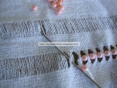 some pink beads are laying on top of a piece of fabric with a pair of scissors