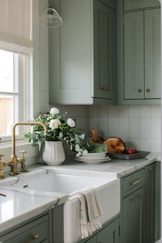 a white sink sitting under a window next to a green kitchen counter top and cabinets