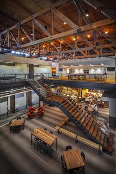 the inside of a building with tables, benches and stairs leading up to an open floor plan