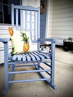 a blue rocking chair with a pineapple pillow sitting on it's seat in front of a house