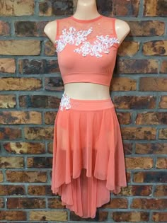 a woman's skirt and top are on display in front of a brick wall