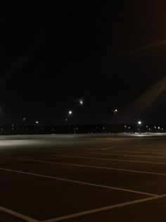 an empty parking lot at night with street lights in the distance and no cars on it