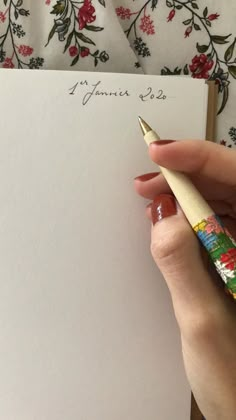 a person holding a pen and writing on a piece of paper with flowers in it