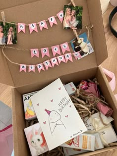 an open box filled with photos and pink buntings on top of a wooden table