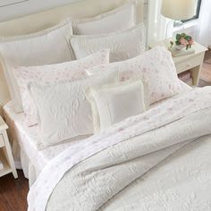 a bed with white comforter and pillows on it