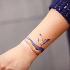 a woman's arm with a bird tattoo on it