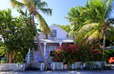 a white house surrounded by palm trees and flowers