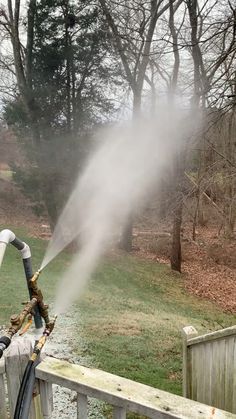 a fire hydrant spewing water onto a wooden deck in front of trees