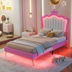 a pink bed with stars and moon lights on the headboard is in a bedroom