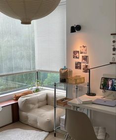 a living room with a couch, desk and television on the wall next to a window