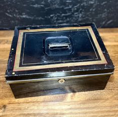 an old metal box sitting on top of a wooden table