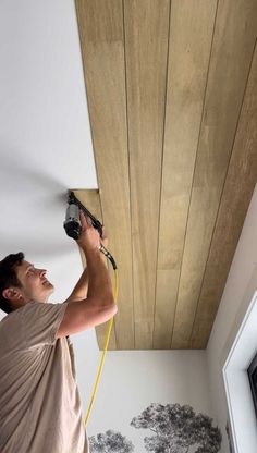 a man is using a paint roller to paint the wood paneling on the ceiling