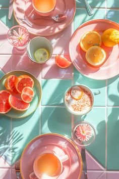 pink plates with oranges, lemons and other food on them sitting on a tiled floor