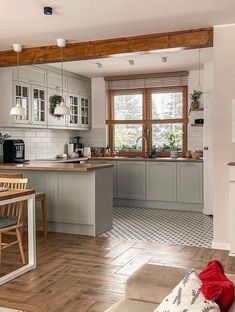 an open kitchen and dining room with wood flooring, white walls and gray cabinets