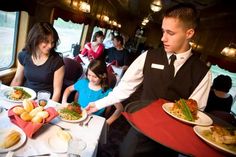 a waiter serving food to diners in a dining car on a train or boat