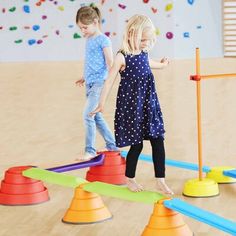 two young children playing in an indoor play area with cones and colored markers on the floor