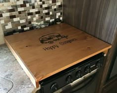 a wooden cutting board on top of an oven in a kitchen with tile backsplash