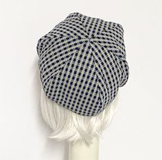 a white mannequin head wearing a black and white checkered newsboy hat