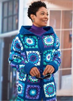 a woman wearing a blue crocheted jacket and purple turtle neck sweater