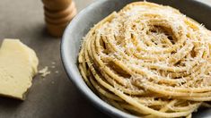 a bowl filled with lots of pasta next to a piece of cheese on top of a table