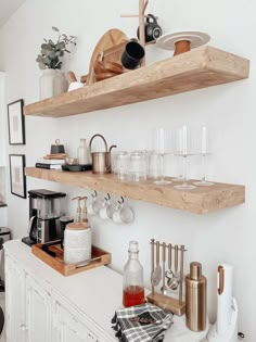 two wooden shelves filled with dishes and cups on top of a white kitchen countertop