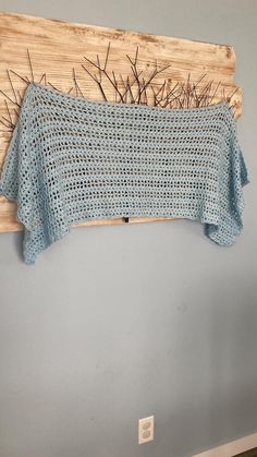 a blue crocheted sweater hanging on a wall