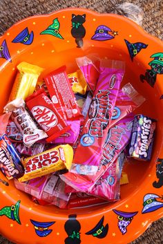 an orange bowl filled with candy on top of a carpet