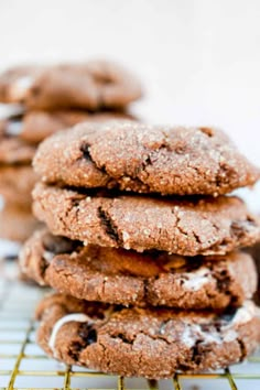 a stack of chocolate cookies sitting on top of a cooling rack next to each other