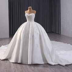 a white wedding dress on display in front of a curtain