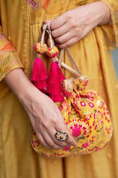 "Our Alanna potli is detailed with thread and zari and sequin embroidery on soft silk. Pair this with a vibrant pink ensemble and watch it stand out as a statement accessory! Colour: Mustard with pink Embroidered front and back. Dimensions (LxB): 8.5\"×9.5\" Handle drop: 5\" Material : Embroidered silk, gold tissue, poly satin lining, woven gold thread drawstrings and silk thread tassle detailing." Outfit For Haldi, Potlis Bags, Pumpkin Patch Outfit, Potli Bag, Embroidered Handbag, Bags Patterns, Floral Clutches, Potli Bags, Embroidery Bags