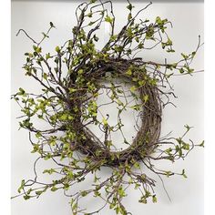 a twig wreath hanging on the wall with green leaves and twigs around it, ready to be used as an ornament