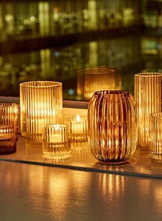 candles are lined up on a window sill in front of a cityscape