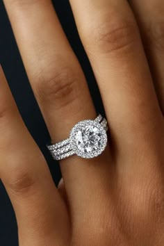 a woman's hand with a diamond engagement ring on top of her wedding band