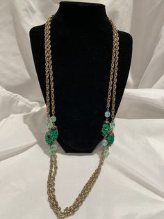 This stunning statement piece is a vintage signed Coro opera length necklace.  The glimmering green oval beads are flanked by cut iridescent beads, which adorn a 60-inch gold tone chain.   Whether worn long or doubled, it's a show-stopper. Elegant Green Oval Bead Necklaces, Elegant Green Oval Beaded Necklaces, Elegant Green Necklaces With Oval Beads, Green Long Metal Necklace, Green Oval Beaded Jewelry, Oval Green Beaded Jewelry, Vintage Green Necklace With Chain, Elegant Green Oval Beads Jewelry, Green Oval Jewelry For Evening