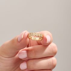 a woman's hand holding a gold ring