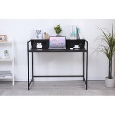 a desk with a laptop computer on top of it next to a potted plant