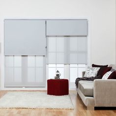 a living room with a couch, chair and table in front of a window that has blind shades on it